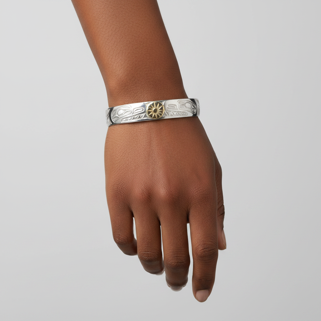 A 10mm silver-toned cuff bracelet with engraved tribal-style patterns and a central gold-toned sun medallion, shown on a plain white background.