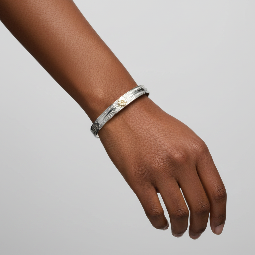 A 7mm width silver-toned open cuff bracelet with engraved floral and leaf motifs and a small gold-toned flower detail at the center, shown on a plain white background.