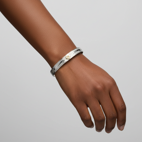 A 7mm width silver-toned open cuff bracelet with engraved floral and leaf motifs and a small gold-toned flower detail at the center, shown on a plain white background.