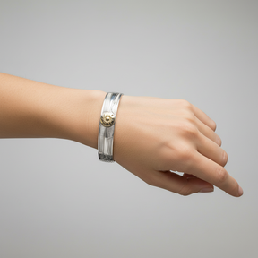 A 10mm width silver-toned cuff bracelet with engraved leaf and branch patterns and a central gold-toned sunburst flower detail, shown on a plain white background.