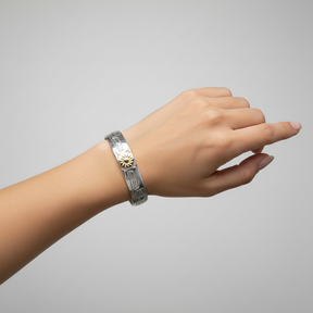 A 10mm width silver-toned cuff bracelet with engraved patterns and a central gold-toned sunburst emblem, shown on a plain white background.