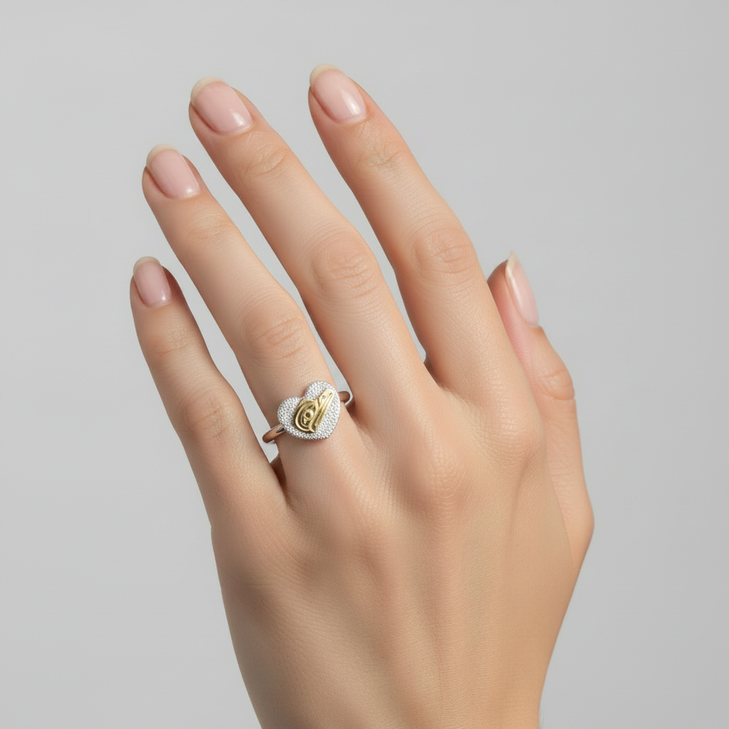 Heart-shaped ring with gold and silver design on a white background